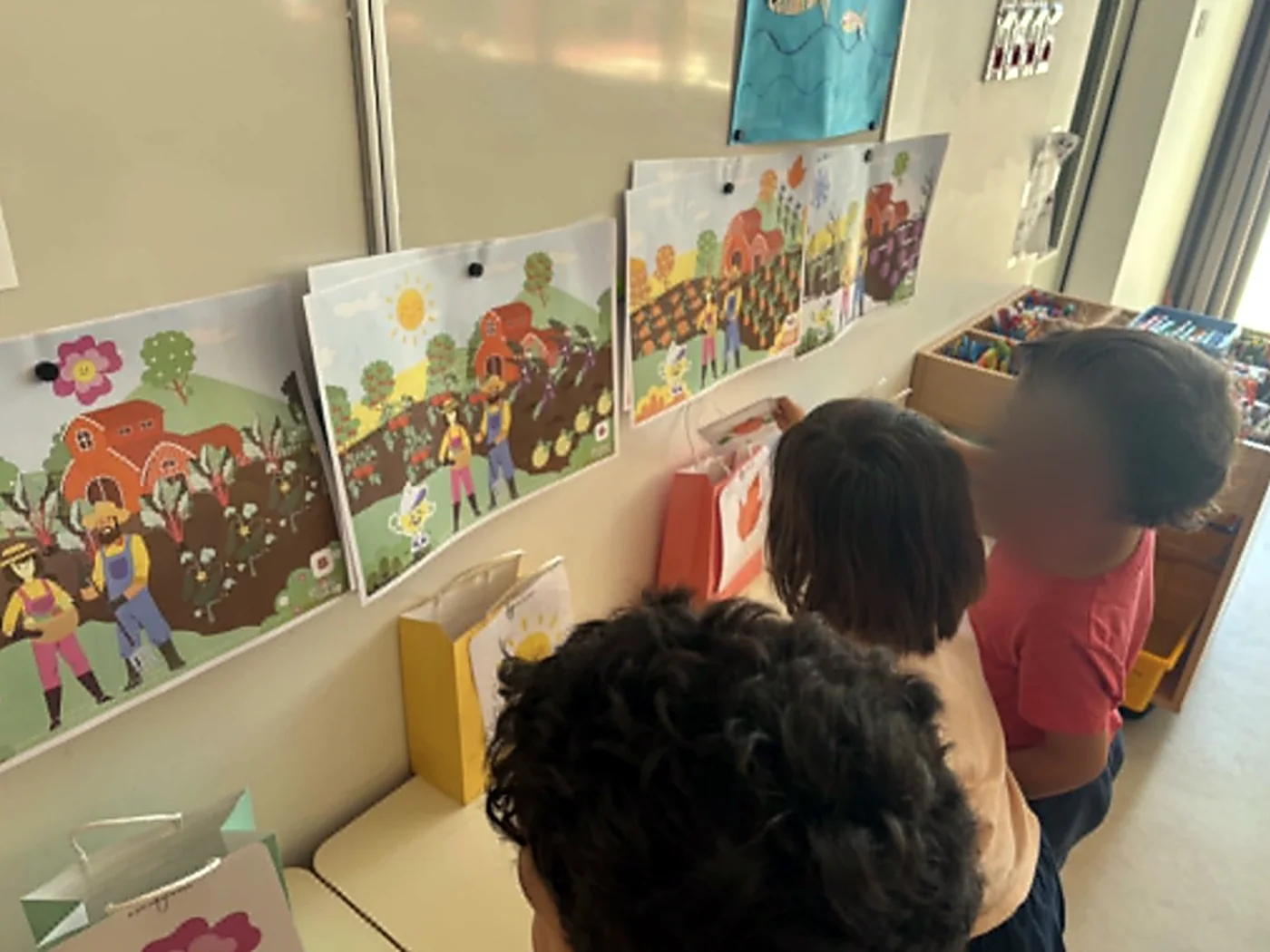 Des élèves de maternelle observent les affiches des saisons accrochées au mur de la classe.