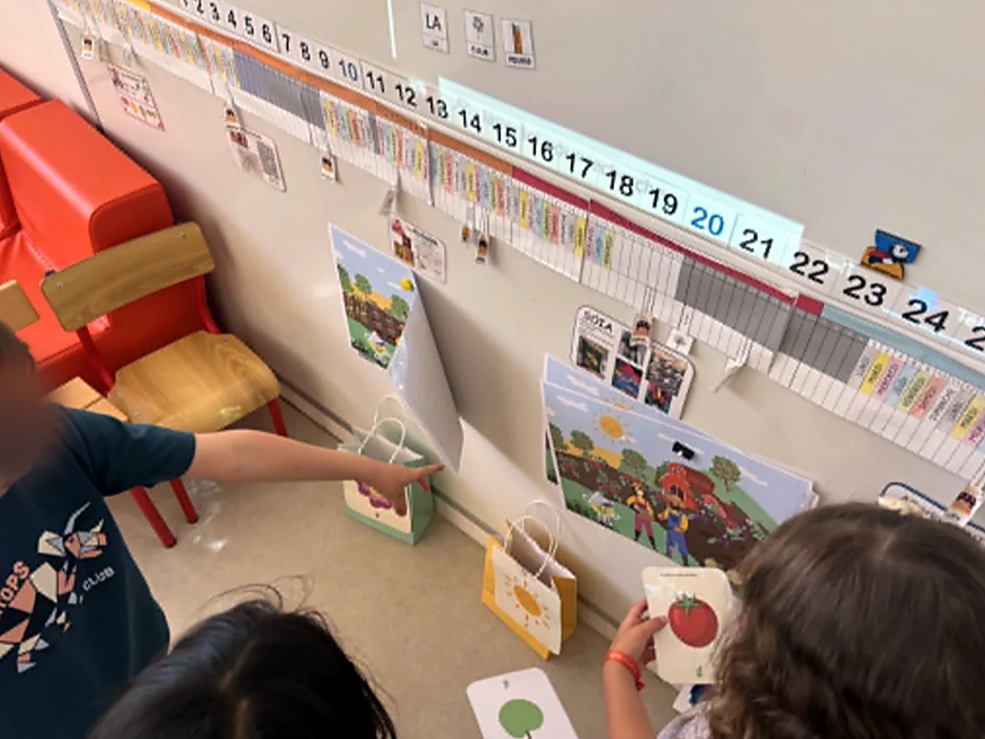 Des élèves classent les cartes aliments par saison devant les affiches de la classe.